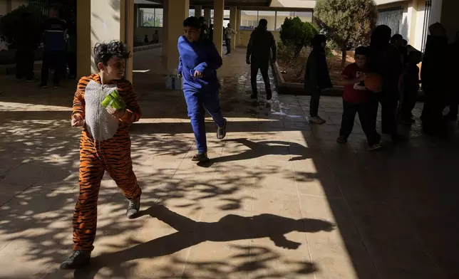 Displaced children, who fled Baalbek city and the nearby towns of Douris and Ain Bourday with their families amid the ongoing Hezbollah-Israel war, play at a school being used as a shelter, in Deir Al-Ahmar, east Lebanon, Thursday, Oct. 31, 2024. (AP Photo/Hassan Ammar)