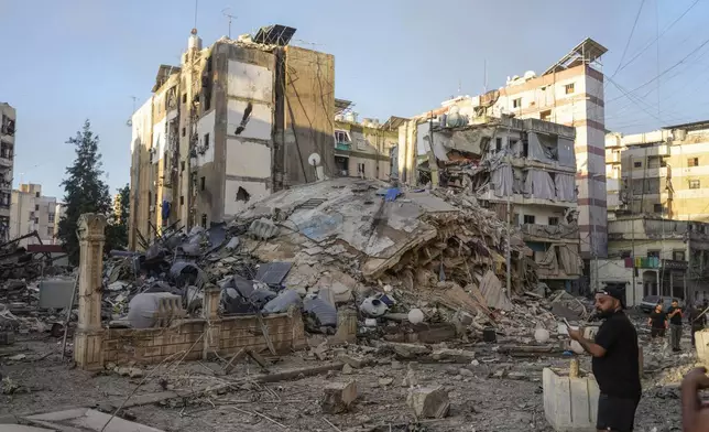 A man documents the damaged buildings at the site of an Israeli airstrike in Dahiyeh, Beirut, Lebanon, Friday, Oct. 4, 2024. (AP Photo/Hassan Ammar)