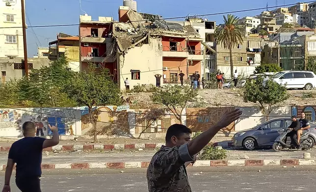 A Lebanese soldier asks journalists to move away from the scene near a building hit in an Israeli airstrike, in the southern port city of Sidon, Lebanon, Sunday, Oct. 27, 2024. (AP Photo/Mohammad Zaatari)