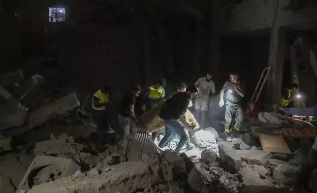 People carry a body at the scene of destroyed buildings hit by an Israeli airstrike in central Beirut, Lebanon, Thursday, Oct. 10, 2024. (AP Photo/Bilal Hussein)