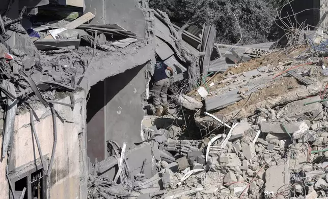 A civil defence worker searches for victims in the rubble of a destroyed building hit in an Israeli airstrike on Tuesday night, in Sarafand, southern Lebanon, Wednesday, Oct. 30, 2024. (AP Photo/Bilal Hussein)