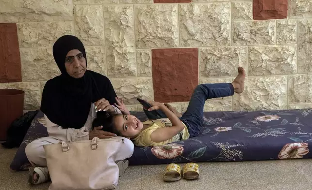 A displaced woman sits with her daughter at a vocational training center run by the U.N. agency for Palestinian refugees, or UNRWA, in the southern town of Sebline, south of Beirut, Lebanon, Friday, Oct. 4, 2024, after fleeing the Israeli airstrikes in the south. (AP Photo/Bilal Hussein)