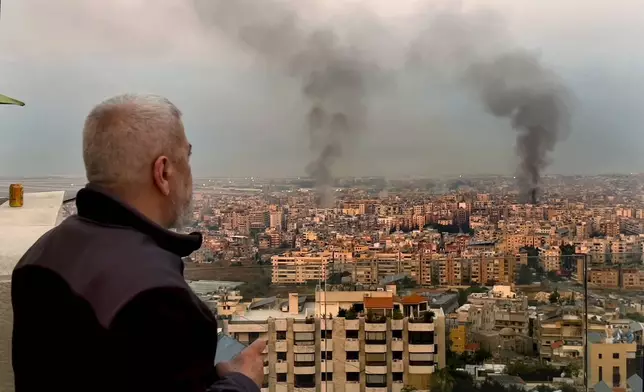 A man looks as smoke rise from Israeli airstrikes in Dahiyeh, Beirut, Lebanon, early Sunday, Oct. 6, 2024. (AP Photo/Hussein Malla)