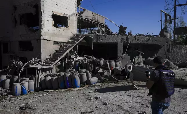 A journalist documents the damaged buildings at the site of an Israeli airstrike, in the village of Temnin, Bekaa Valley, eastern Lebanon, Saturday, Oct. 5, 2024. (AP Photo/Hassan Ammar)