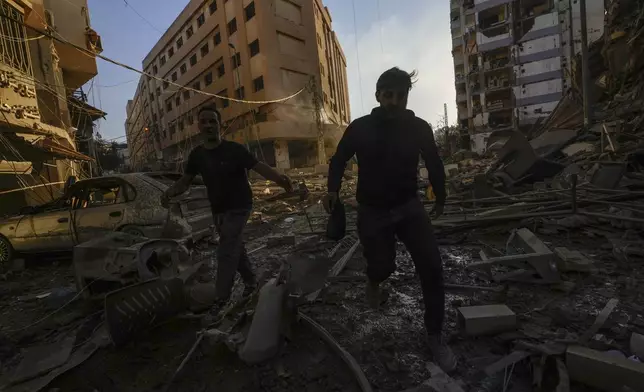 Residents run for cover following an Israeli airstrike in Dahiyeh, Beirut, Lebanon, Friday, Oct. 4, 2024. (AP Photo/Hassan Ammar)