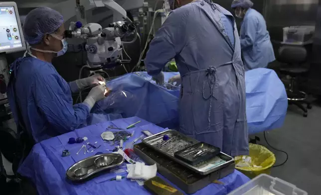 FILE - Elias Jaradeh, a legislator and an ophthalmologist, left, who has conducted dozens of operation for victims of this week's attack in Lebanon, makes an eye surgery operation for a man who was injured in the explosion of one of the handheld devices, at the Eye Specialist hospital, in Beirut, Lebanon, Friday, Sept. 20, 2024. (AP Photo/Hussein Malla, File)