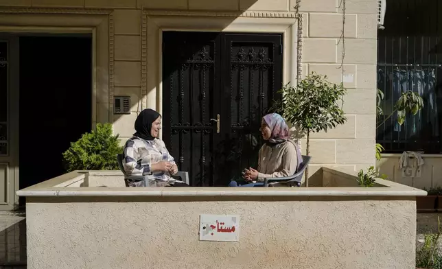 Zeinab Jaber, left, and her sister Fatima who were displaced from Mhaibib, a Lebanese border village with Israel, speak as they sit at the entrance of their house in Aramoun village, southeast of Beirut, Lebanon, Saturday, Oct. 26, 2024. (AP Photo/Bilal Hussein)