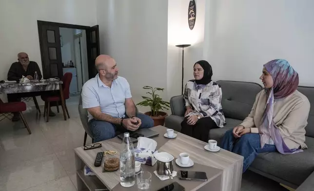 Members of a displaced family, who fled from an Israeli airstrike in Mhaibib, a Lebanese border village with Israel, share memories of their village as they sit in their house in Aramoun village, southeast of Beirut, Lebanon, Saturday, Oct. 26, 2024. (AP Photo/Bilal Hussein)