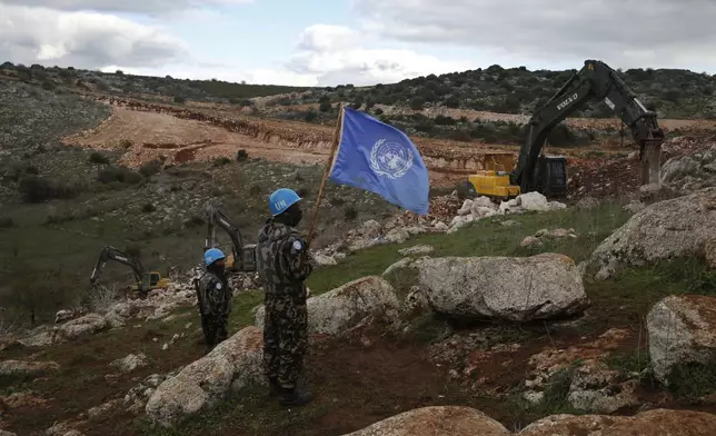 FILE - UN peacekeepers hold their flag, as they observe Israeli excavators attempt to destroy tunnels built by Hezbollah, near the southern Lebanese-Israeli border village of Mays al-Jabal, Lebanon, Dec. 13, 2019. (AP Photo/Hussein Malla, File)