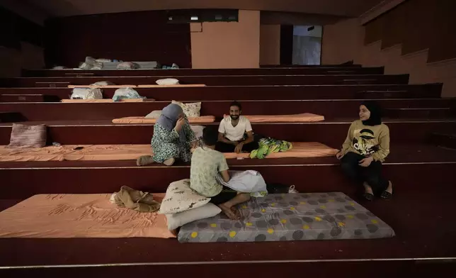 A displaced family, who fled the ongoing Hezbollah-Israel war in south Lebanon, sit on mattresses inside one of Beirut's oldest and best known movie theatres, Le Colisee, where they have taken shelter, in Beirut, Lebanon, Tuesday, Oct. 22, 2024. (AP Photo/Hussein Malla)