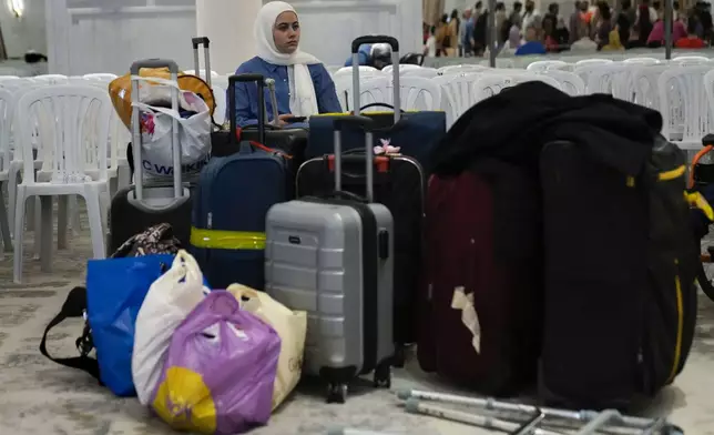 A Turkish citizen sits next of her belongings, as she waits to board a Turkish navy vessel to be evacuated to Turkey at a gathering point, in Beirut, Lebanon, Wednesday, Oct. 9, 2024. (AP Photo/Hussein Malla)