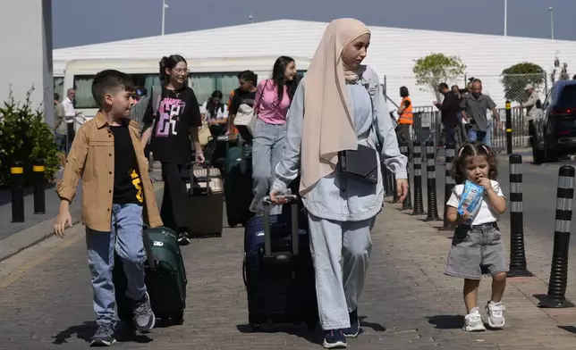 Turkish citizens carry their belongings, as they arrive at a gathering point to board a Turkish navy vessel to be evacuated to Turkey, in Beirut, Lebanon, Wednesday, Oct. 9, 2024. (AP Photo/Hussein Malla)