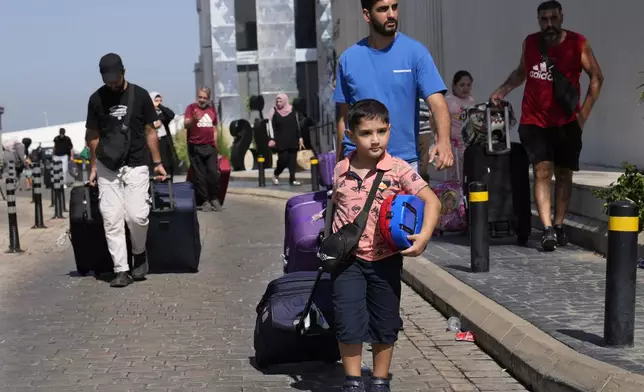 Turkish citizens carry their belongings, as they arrive at a gathering point to board a Turkish navy vessel to be evacuated to Turkey, in Beirut, Lebanon, Wednesday, Oct. 9, 2024. (AP Photo/Hussein Malla)