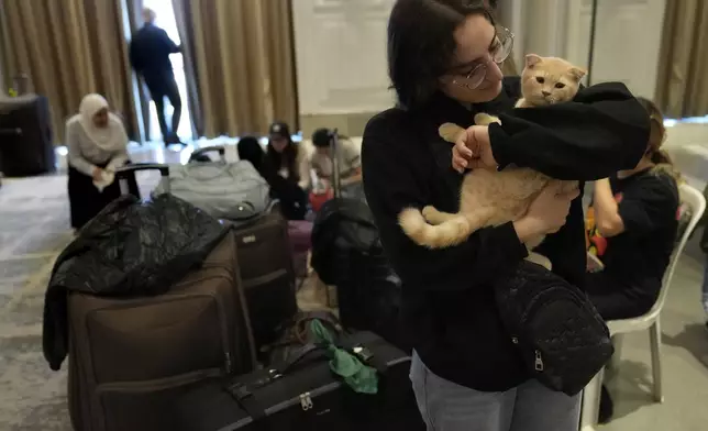 A Turkish citizen hugs her cats as she waits at a gathering point to board a Turkish navy vessel before being evacuated to Turkey, in Beirut, Lebanon, Wednesday, Oct. 9, 2024. (AP Photo/Hussein Malla)