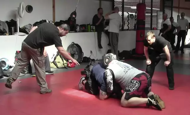 In this image from video made by the Evansville Police Department, police recruit Tanner Corum, below, undergoes training with Mike Fisher, a sheriff's major from a nearby county, during "Big Fight" day for the Southwest Indiana Law Enforcement Academy in Evansville, Ind., on March 2, 2023. (Evansville Police Department via AP)