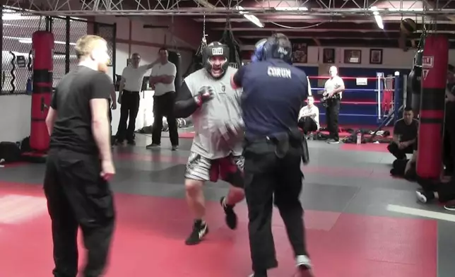 In this image from video made by the Evansville Police Department, police recruit Tanner Corum, foreground right, undergoes training with Mike Fisher, a sheriff's major from a nearby county, during "Big Fight " day for the Southwest Indiana Law Enforcement Academy in Evansville, Ind., on March 2, 2023. (Evansville Police Department via AP)