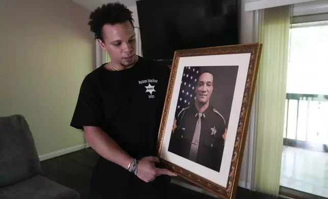 Lij Hacker holds a photo of his late brother, Asson Hacker, during an interview in Bloomington, Ind., on June 4, 2024. (AP Photo/Darron Cummings)