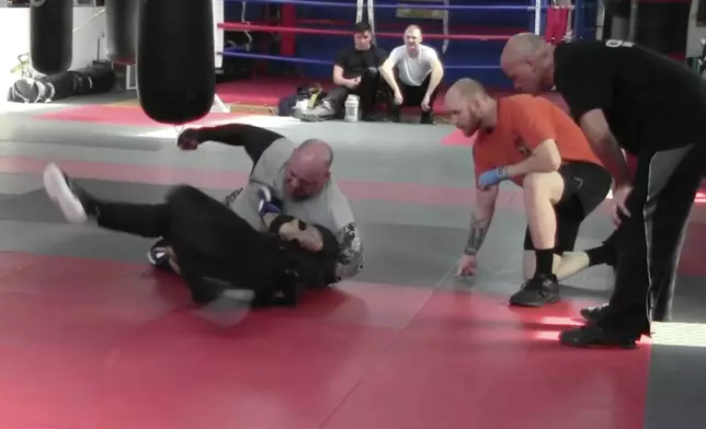 In this image from video made by the Evansville Police Department, rookie sheriff’s Deputy Asson Hacker, below left, undergoes training with Mike Fisher, a sheriff's major from a nearby county, during "Big Fight " day for the Southwest Indiana Law Enforcement Academy in Evansville, Ind., on March 2, 2023. (Evansville Police Department via AP)