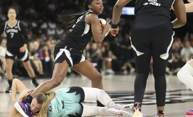 Las Vegas Aces guard Jackie Young (0) attempts to step over New York Liberty guard Sabrina Ionescu (20) during the first half of a WNBA Semifinal basketball game, Sunday, Oct. 6, 2024, in Las Vegas. (AP Photo/Ian Maule)