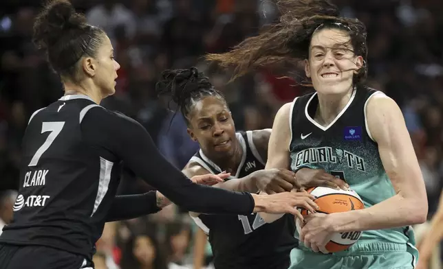 New York Liberty forward Breanna Stewart wrestles a rebound away from Las Vegas Aces forward Alysha Clark and guard Chelsea Gray during the second half of a WNBA Semifinal basketball game, Sunday, Oct. 6, 2024, in Las Vegas. (AP Photo/Ian Maule)