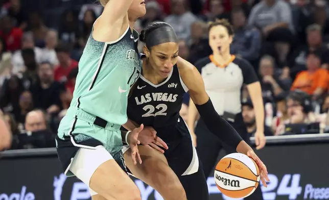 Las Vegas Aces center A'ja Wilson (22) drives the ball around New York Liberty forward Leonie Fiebich (13) during a WNBA basketball semifinal game Friday, Oct. 4, 2024, in Las Vegas. (AP Photo/Ronda Churchill)