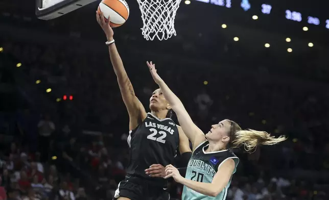 Las Vegas Aces center A'ja Wilson (22) goes up for a basket over New York Liberty guard Sabrina Ionescu (20) during the first half of a WNBA Semifinal basketball game, Sunday, Oct. 6, 2024, in Las Vegas. (AP Photo/Ian Maule)