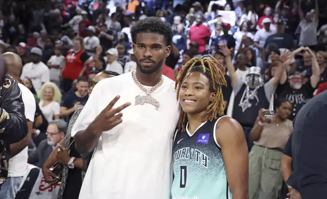 New York Liberty guard Jaylyn Sherrod (0) poses for a photo with Colorado Buffaloes quarterback Shedeur Sanders after playing in a WNBA basketball semifinal game against Las Vegas Aces, Friday, Oct. 4, 2024, in Las Vegas. (AP Photo/Ronda Churchill)