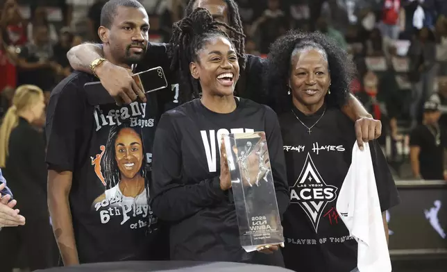 Las Vegas Aces guard Tiffany Hayes celebrates receiving the WMBA Sixth Player of the Year award with her mother and brothers prior to playing in a WNBA basketball semifinal game against New York Liberty Friday, Oct. 4, 2024, in Las Vegas. (AP Photo/Ronda Churchill)
