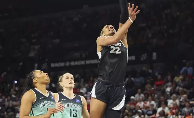 Las Vegas Aces center A'ja Wilson (22) shoots the ball near New York Liberty's Betnijah Laney-Hamilton (44) and Leonie Fiebich (13) during a WNBA basketball semifinal game, Friday, Oct. 4, 2024, in Las Vegas. (AP Photo/Ronda Churchill)