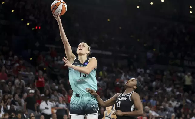 New York Liberty forward Leonie Fiebich goes up for a basket past Las Vegas Aces guard Jackie Young (0) during the second half of a WNBA Semifinal basketball game, Sunday, Oct. 6, 2024, in Las Vegas. (AP Photo/Ian Maule)