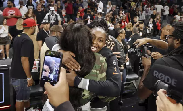 Las Vegas Aces guard Chelsea Gray (12) embraces former WMBA's Sheryl Swoopes after playing in a WNBA basketball semifinal game against New York Liberty Friday, Oct. 4, 2024, in Las Vegas. (AP Photo/Ronda Churchill)