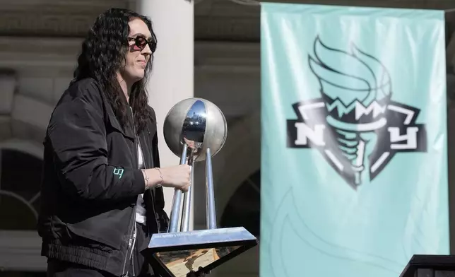 New York Liberty Breanna Stewart places the championship trophy on a table as she arrives on stage during a ceremony after a parade in honor of the Liberty's WNBA basketball championship at City Hall in New York, Thursday, Oct. 24, 2024. (AP Photo/Seth Wenig)