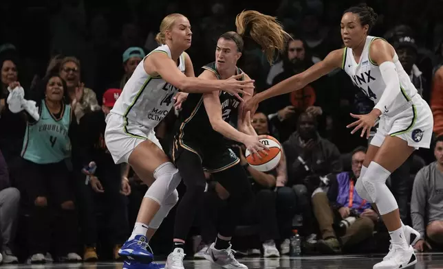 New York Liberty guard Sabrina Ionescu (20) is double teamed by Minnesota Lynx forward Dorka Juhasz (14) and forward Napheesa Collier (24) during the third quarter of Game 5 of the WNBA basketball final series, Sunday, Oct. 20, 2024, in New York. (AP Photo/Pamela Smith)