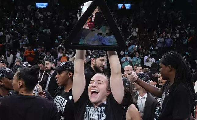 New York Liberty guard Sabrina Ionescu holds up the championship trophy after the Liberty defeated the Minnesota Lynx in Game 5 of the WNBA basketball final series, Sunday, Oct. 20, 2024, in New York. (AP Photo/Pamela Smith)