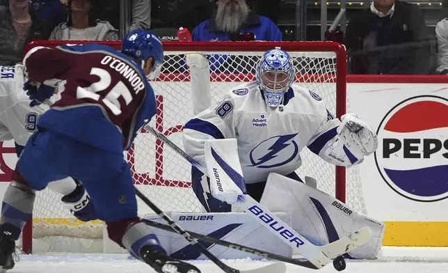 Colorado Avalanche right wing Logan O'Connor, front, fires the puck at Tampa Bay Lightning goaltender Andrei Vasilevskiy in the second period of an NHL hockey game, Wednesday, Oct. 30, 2024, in Denver. (AP Photo/David Zalubowski)