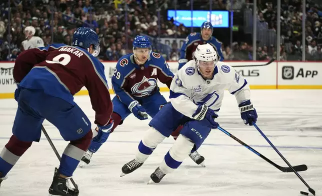Tampa Bay Lightning center Brayden Point, right, drives witht he puck past Colorado Avalanche defenseman Cale Makar, front left, and center Nathan MacKinnon in the second period of an NHL hockey game Wednesday, Oct. 30, 2024, in Denver. (AP Photo/David Zalubowski)