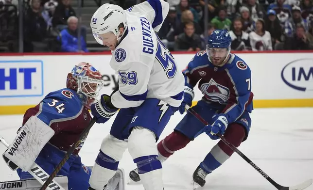 Tampa Bay Lightning center Jake Guentzel, front, scores a goal past Colorado Avalanche goaltender Kaapo Kahkonen, back left, after driving past defenseman Devon Toews in the second period of an NHL hockey game Wednesday, Oct. 30, 2024, in Denver. (AP Photo/David Zalubowski)
