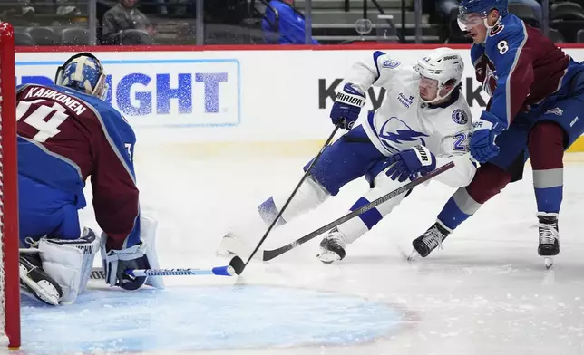Tampa Bay Lightning center Michael Eyssimont, center, directs a shot at Colorado Avalanche goaltender Kaapo Kahkonen, left, after driving past defenseman Cale Makar in the second period of an NHL hockey game Wednesday, Oct. 30, 2024, in Denver. (AP Photo/David Zalubowski)
