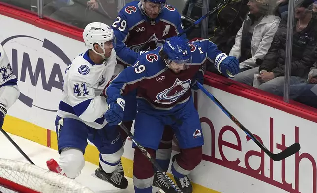 Tampa Bay Lightning right wing Mitchell Chaffee, front left, fights for control of the puck with Colorado Avalanche defenseman Samuel Girard, right, and center Nathan MacKinnon in the first period of an NHL hockey game Wednesday, Oct. 30, 2024, in Denver. (AP Photo/David Zalubowski)