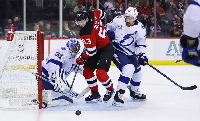 New Jersey Devils left wing Jesper Bratt (63) plays the puck against Tampa Bay Lightning goaltender Jonas Johansson (31) and defenseman Ryan McDonagh (27) during the second period of a NHL hockey game, Tuesday Oct. 22, 2024, in Newark, N.J. (AP Photo/Noah K. Murray)