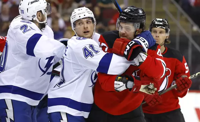 Tampa Bay Lightning right wing Mitchell Chaffee (41) holds New Jersey Devils center Paul Cotter (47) after a scuffle with Nicholas Paul (20) during the second period of a NHL hockey game, Tuesday Oct. 22, 2024, in Newark, N.J. (AP Photo/Noah K. Murray)