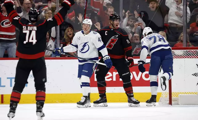 Carolina Hurricanes' Jordan Staal (11) celebrates after his goal between Tampa Bay Lightning's Darren Raddysh (43) and Emil Lilleberg (78) with Hurricanes' Jaccob Slavin (74) nearby during the first period of an NHL hockey game in Raleigh, N.C., Friday, Oct. 11, 2024. (AP Photo/Karl B DeBlaker)