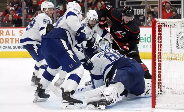 Carolina Hurricanes' Andrei Svechnikov (37) battles for the puck with Tampa Bay Lightning's Jake Guentzel (59), Nikita Kucherov (86), Ryan McDonagh (27) and goaltender Andrei Vasilevskiy (88) during the second period of an NHL hockey game in Raleigh, N.C., Friday, Oct. 11, 2024. (AP Photo/Karl B DeBlaker)