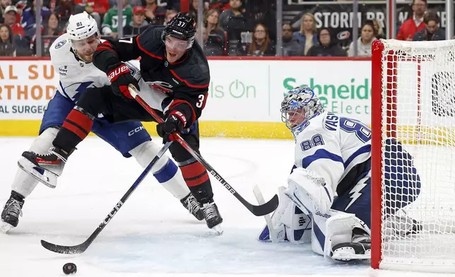 Carolina Hurricanes' Andrei Svechnikov (37) battles with Tampa Bay Lightning's Erik Cernak (81) for the puck in front of Lightning goaltender Andrei Vasilevskiy (88) during the second period of an NHL hockey game in Raleigh, N.C., Friday, Oct. 11, 2024. (AP Photo/Karl B DeBlaker)