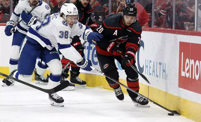 Carolina Hurricanes' Sebastian Aho (20) battles for the puck with Tampa Bay Lightning's Brandon Hagel (38) during the first period of an NHL hockey game in Raleigh, N.C., Friday, Oct. 11, 2024. (AP Photo/Karl B DeBlaker)