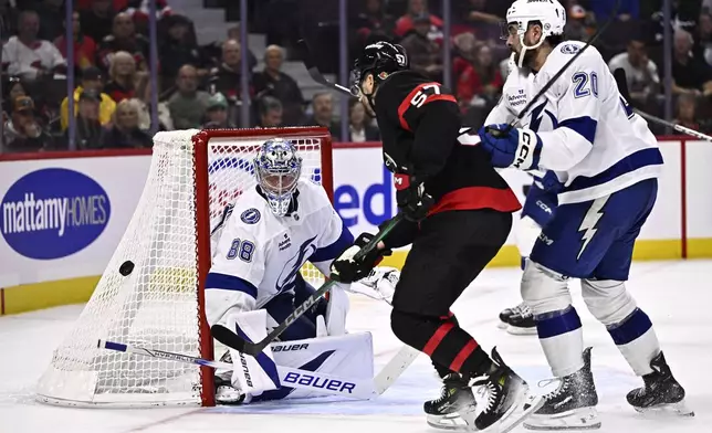 Tampa Bay Lightning goaltender Andrei Vasilevskiy (88) watches as Ottawa Senators left wing David Perron (57) and Tampa Bay Lightning left wing Nicholas Paul (20) chase the puck as it bounces behind the net during the second period of an NHL hockey game in Ottawa, Saturday, Oct. 19, 2024. (Justin Tang/The Canadian Press via AP)