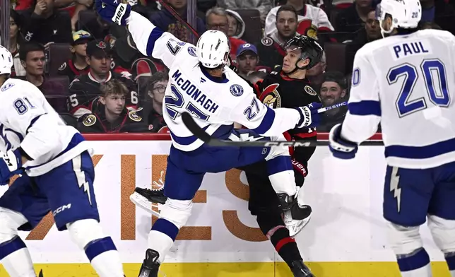 Tampa Bay Lightning defenseman Ryan McDonagh (27) and Ottawa Senators center Tim Stutzle (18) crash into the boards during the second period of an NHL hockey game in Ottawa, Saturday, Oct. 19, 2024. (Justin Tang/The Canadian Press via AP)