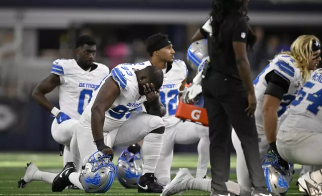 Detroit Lions players kneel on the field as Aidan Hutchinson, not pictured, is attended to by staff afer suffering an unkown injury second half of an NFL football game against the Dallas Cowboys in Arlington, Texas, Sunday, Oct. 13, 2024. (AP Photo/Jerome Miron)