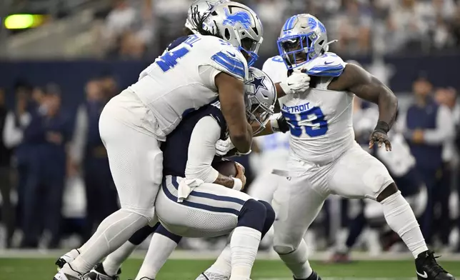 Detroit Lions defensive tackle Alim McNeill, left, sacks Dallas Cowboys quarterback Dak Prescott (4) as Josh Paschal (93) pressures in the first first half of an NFL football game in Arlington, Texas, Sunday, Oct. 13, 2024. (AP Photo/Jerome Miron)