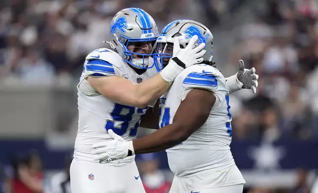 Detroit Lions defensive end Aidan Hutchinson (97) and Alim McNeill, right, celebrate after McNeill sacked Dallas Cowboys' Dak Prescott (4) in the first half of an NFL football game in Arlington, Texas, Sunday, Oct. 13, 2024. (AP Photo/LM Otero)